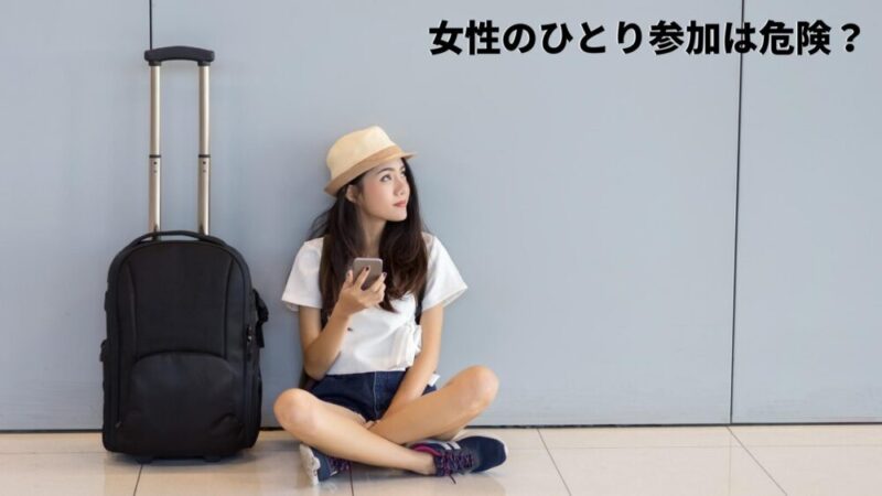 旅行バックを置いて座っている女性